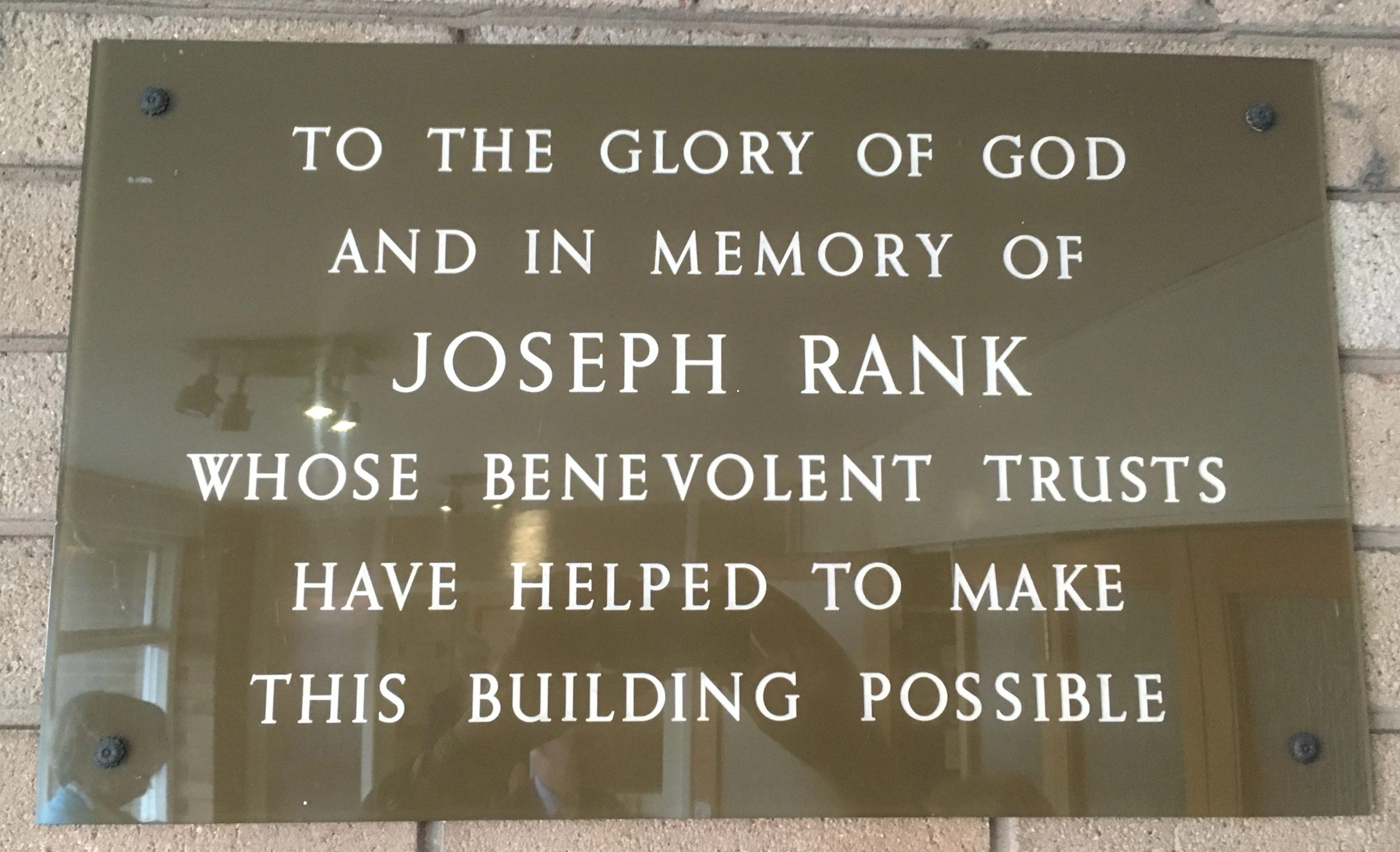 Brown perspex plaque with white lettered inscription to Joseph Rank commemorating the 1967 building of Lindale Methodist Church