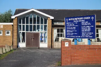 Modern yellow brick church building, with large rectangular plain glass windows