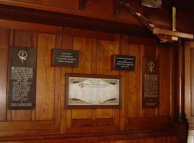 A collection of plaques and a framed roll of honour hanging on a wooden clad wall in Raikes Parade Methodist Church
